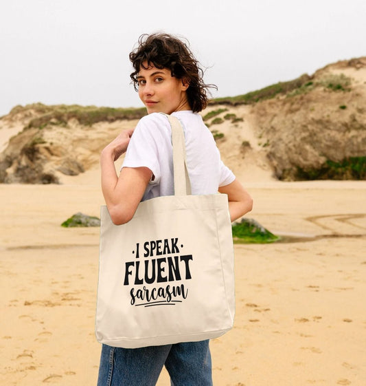 White tote bag with "I SPEAK FLUENT sarcasm" text (person)