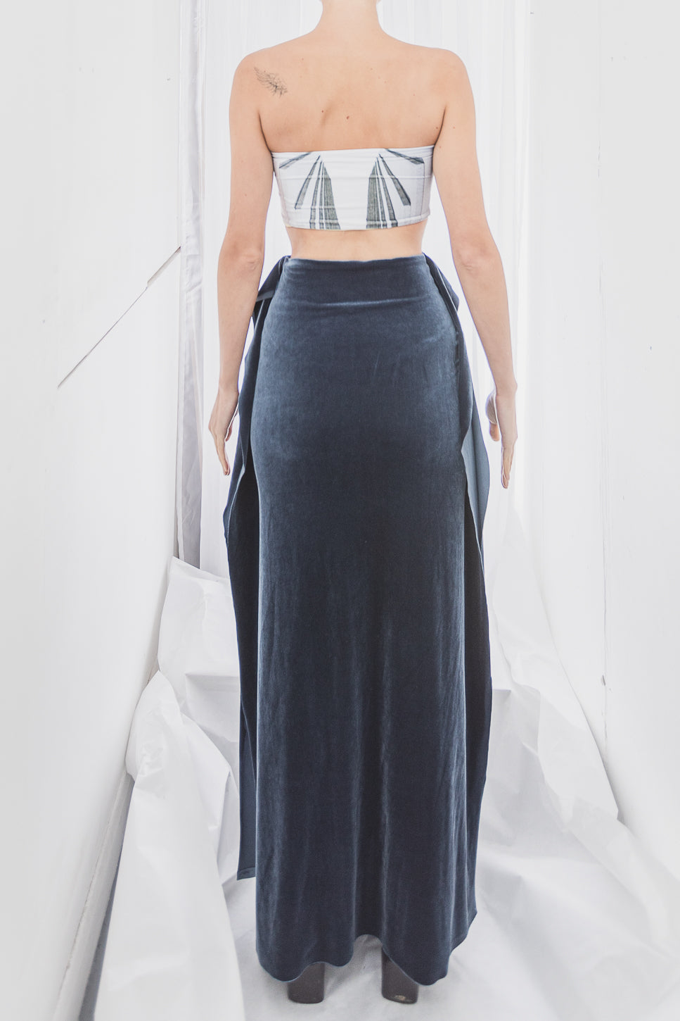 Strapless top with geometric pattern and long, dark blue velvet skirt (person)
