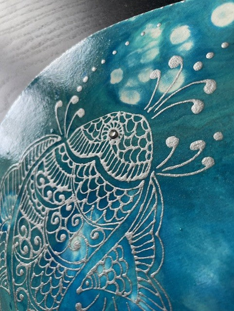 Intricate fish design on blue ceramic plate