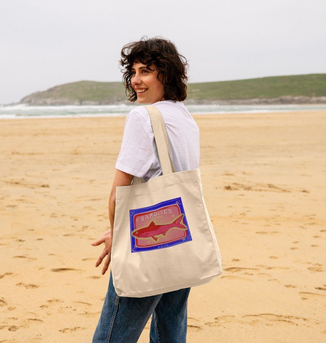 Natural canvas tote bag with "SARDINES" and fish graphic (person)