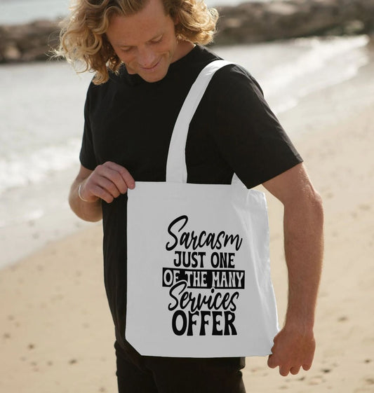 White tote bag with "Sarcasm Just One of the Many Services Offer" text (person)