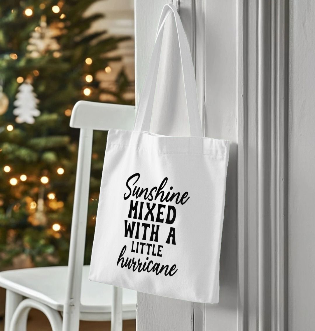 White tote bag with "Sunshine Mixed With A Little Hurricane" text